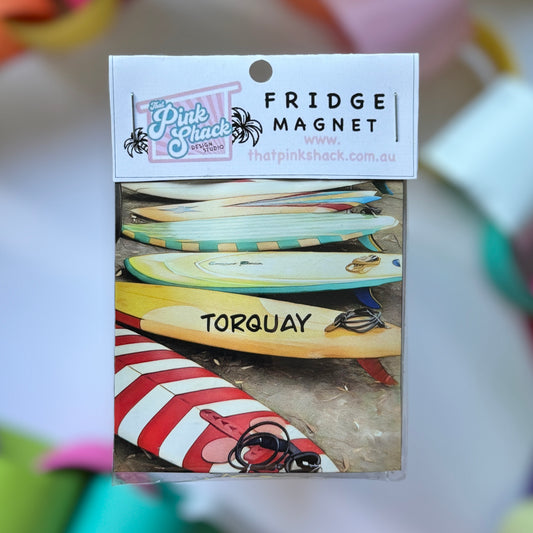 A Torquay fridge magnet with a collection of vintage surfboards in packaging